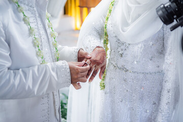 Bride and groom exchanging rings during a traditional Indonesian wedding ceremony, symbolizing their commitment and love. Asian muslim wedding