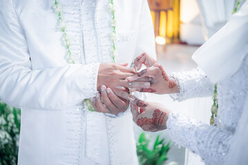 Bride and groom exchanging rings during a traditional Indonesian wedding ceremony, symbolizing their commitment and love. Asian muslim wedding