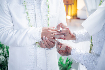 Bride and groom exchanging rings during a traditional Indonesian wedding ceremony, symbolizing their commitment and love. Asian muslim wedding