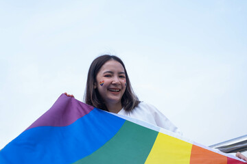 A joyful individual celebrates with a vibrant rainbow flag, symbolizing pride and inclusivity,...