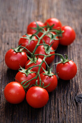 Fresh Tomatoes on twigs lying on a wooden table, close up view