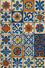 A vibrant collection of decorative tiles. The tiles display a pattern of flowers, swirls, and geometric shapes in a handmade style.