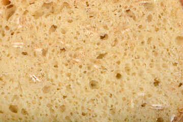 A close-up of a slice of homemade bread with muesli, revealing its texture and bits of ingredients