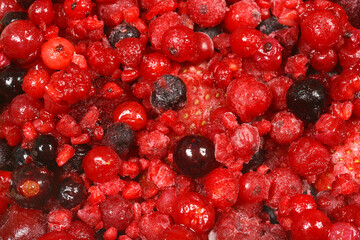 A close-up view of a vibrant mix of frozen red berries, including cranberries, raspberries, and blackberries, showing their frosty texture