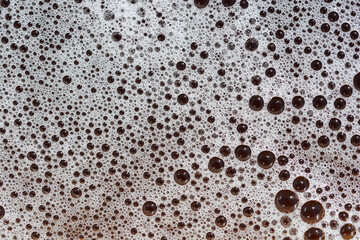A close-up view of foam bubbles of varying sizes, creating an abstract texture