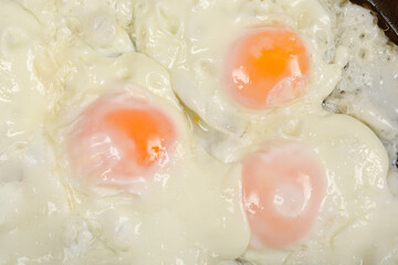 A close-up of fried eggs with set whites and orange yolks