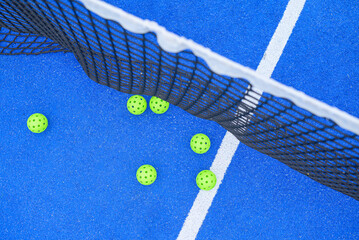 six pickleball balls near the net in a blue court, top down view
