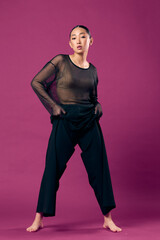 Fashion asian woman in black pants and sheer top posing on purple background