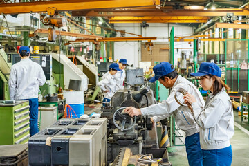 工場で工作機械を操作する作業員グループ