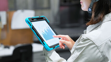 タブレットを持って工場機械を点検する女性作業員