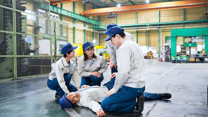 工場で倒れた作業員を救護するグループ