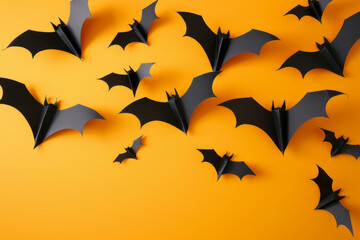 Fototapeta premium Origami bats on an orange background, perfect for Halloween decorations and spooky themes.