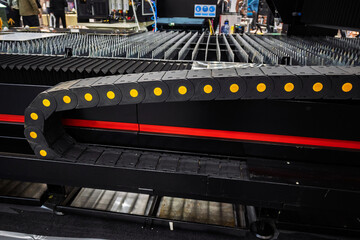The Laser Cutting Machine in Action with a Black Protective Wire Covering and Conveyor System