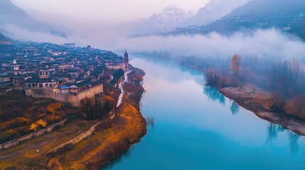 Fototapeta premium Misty village nestled beside a tranquil river.