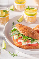 Golden and healthy french croissant with prosciutto, arugula and camembert.