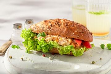 Fresh and healthy sandwich served with lemonade on white board.