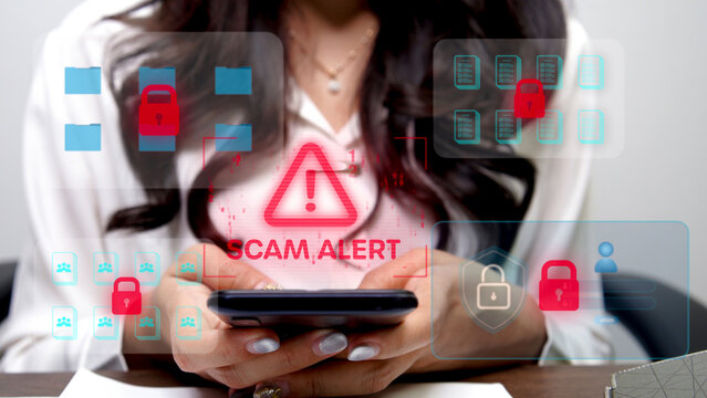 A person in a black shirt is typing on a mobile phone with a futuristic screen displaying a red exclamation symbol, indicating a cyber threat or hacking attempt