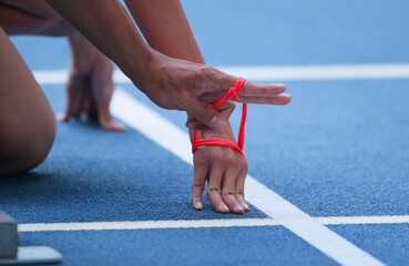 Female para-blind athlete runner with male guide in starting block of running race ready, in para...