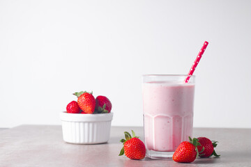 Glass of fresh strawberry milkshake, smoothie and fresh strawberries on white and wooden...