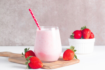 Glass of fresh strawberry milkshake, smoothie and fresh strawberries on white and wooden background. Healthy food and drink concept.
