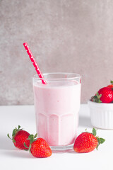 Glass of fresh strawberry milkshake, smoothie and fresh strawberries on white and wooden background. Healthy food and drink concept.