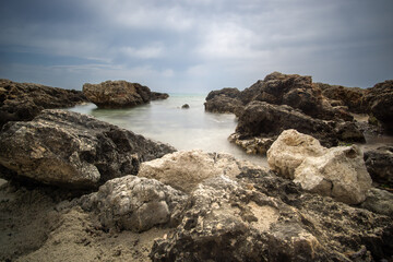 Rugged coastline in Mallorca with rock formations and calm sea under an atmospheric sky in cloudy weather