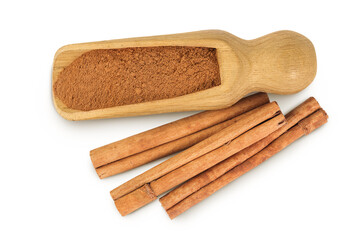 Cinnamon sticks with powder in wooden scoop isolated on white background. Top view. Flat lay.
