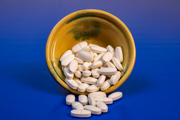 tarro amarillo con pastillas blanca medicina con fondo azul aporte vitaminas