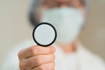 Female doctor in white coat and medical mask holding the stethoscope diaphragm for lung examination. Focus on diagnosing respiratory illnesses, pneumonia, bronchitis, and treatment.