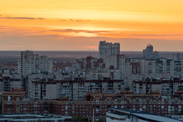 Fototapeta premium urban landscape is illuminated by the orange and pink shades of sunset. Tall and imposing buildings create a sense of awe and wonder. Top view of a multi-storey building.