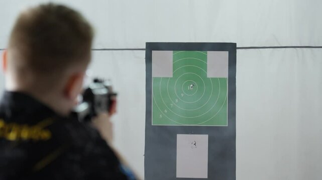Expert marksman engages in intense target practice at an indoor facility. Each shot counts as participants strive for accuracy and technique in a controlled environment. Sport shooting in 4K, UHD