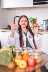 nutritionist in a white coat holding an apple in her hands among fresh products. health concept, fitness.