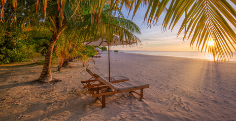 Closeup sunset sky sea sand beach chairs umbrella and palm leaves. Dreamy tropical vacation travel. Luxury seaside escape, romantic coastal view. Summer relaxation best exotic travel paradise getaways