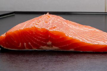 Fresh raw salmon or trout fillet. Fish for sushi. Preparing fish for cooking. Black background. Healthy seafood food.