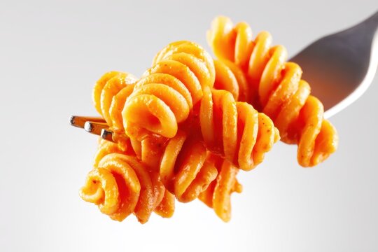 : close-up of fusilli pasta with tomato sauce twirled on a fork, isolated on white. Ideal for food blogs, cooking content, restaurant menus, or Italian cuisine themes.
