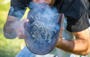 Australian Aboriginal smoking ceremony, human hands and wooden dish with a smoke of burning tree branches, the ritual rite at the community event, symbol of joining to the indigenous culture