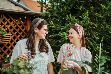 Two female friends or sisters taking care of plants with water can and mister