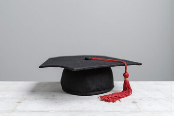 graduation cap with a red tassel on a wooden table
