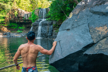 Travel people enjoy beautiful waterfall in tropical rainforest jungle on nature background. Active lifestyle and travel concept 