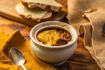 Onion soup in a pot according to a traditional French recipe with a cheese crust, on a wooden...