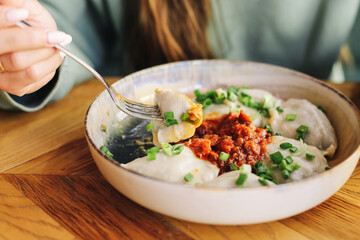 Traditional Polish dumplings. Delicious pierogi with meat filling. Topped with fried onions and green chives. Homemade comfort food. Tasty Eastern European dish on a wooden table in daylight.