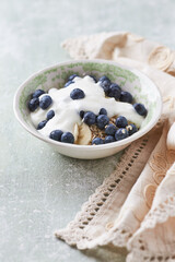 Healthy breakfast bowl with yogurt, blueberries and granola on a bright background. Copy space. 