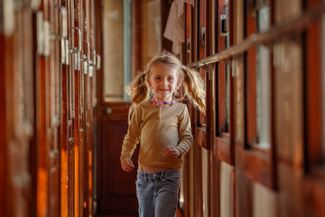 Happy little girl runs joyfully along sunlit train corridor