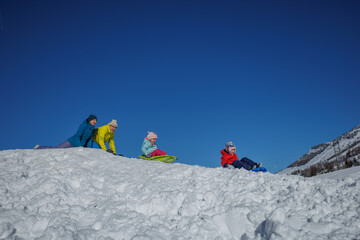 Family enjoys a sunny day sledding on snowy hills