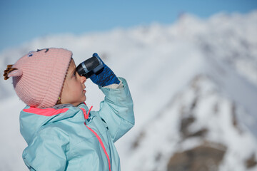 Young explorer girl wear pink hat views snowy peaks in binocular