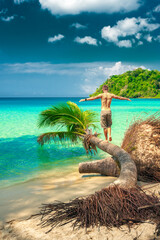 Young man arms outstretched by the sea at sunrise enjoying freedom and life, people travel wellbeing concept