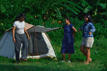The group of girls stands together, observing the tent proudly after successfully completing the setup with teamwork and effort.