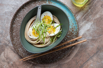 Bowl of miso udon with boiled egg on a brown granite background, horizontal shot with space, top...