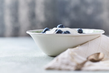 Healthy breakfast bowl with yogurt, blueberries and granola on a bright background. Copy space.