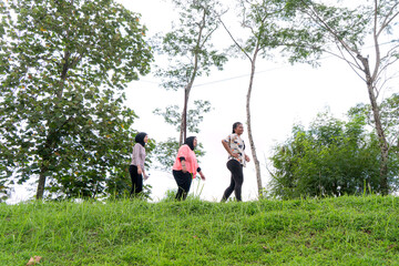 Three Asian Women Walking Together on a Rural Road in Scenic Green Countryside